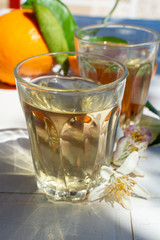 White wine served outside in garden on white table with fresh orange in sun lights