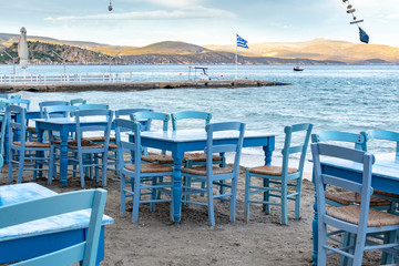 Fototapeta premium Traditional greek tavern with wooden tables on sandy beach near water waiting for tourists in Tolo, Peloponnese, Greece