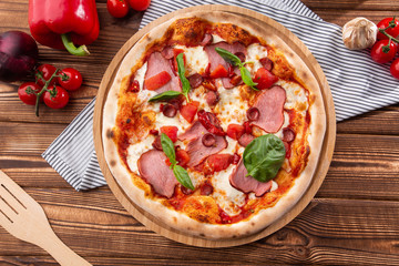 Pizza with ham , arugula (salad rocket), rucola and mozzarella  on  wooden background close up. Italian cuisine.