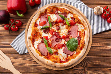 Pizza with ham , arugula (salad rocket), rucola and mozzarella  on  wooden background close up. Italian cuisine.