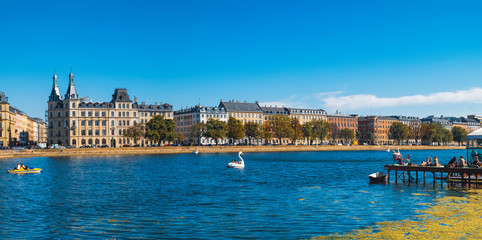 Tourists visiting and enjoying views of Queen Louise's Bridge and Peblinge Lake in central Copenhagen from outdoor cafe, Denmark