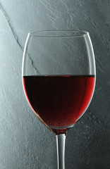 glass with red vine in front of gray background
