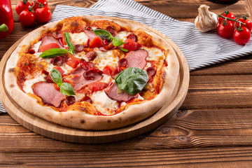 Pizza with ham , arugula (salad rocket), rucola and mozzarella  on  wooden background close up. Italian cuisine.