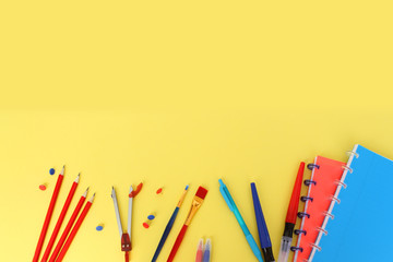 Colored school various stationery, paints, pencils, pens, on a yellow background. Back to school concept, top view, copy space