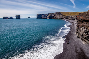 Beautiful sunny day at the coast in Dyrholaei Iceland with black sand and cliffs