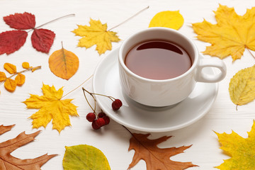 Yellow autumn leaves and a Cup of tea on a white wooden table. Autumn mood concept.