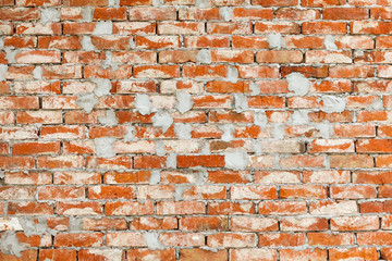 Wall of old, red ceramic brick smeared with cement mortar. Grunge background, texture