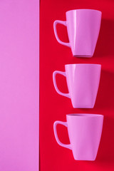 3 pink winter coffee cup mugs lined up in a row for a break time meeting; Copyspace with empty room space for copy text on red vertical background; Girlie female valentines theme.