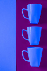 3 blue winter coffee cup mugs lined up in a row for a break time meeting; Copyspace with empty room space for copy text on purple vertical background