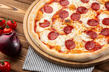 Delicious hot homemade Pepperoni pizza on the wooden table. Pepperoni Pizza - Fresh homemade pizza with pepperoni, cheese and tomato sauce on rustic black stone background wirh copy space.  