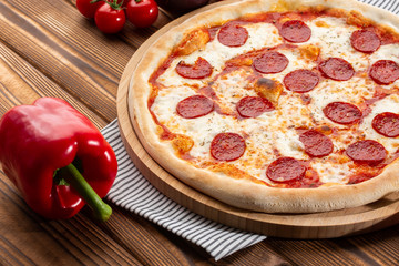 Delicious hot homemade Pepperoni pizza on the wooden table. Pepperoni Pizza - Fresh homemade pizza with pepperoni, cheese and tomato sauce on rustic black stone background wirh copy space.  