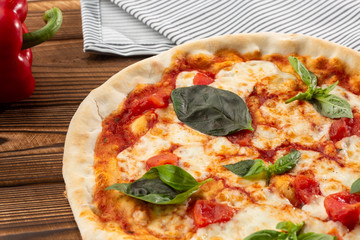 Pizza Margherita on wooden background, top view. Pizza Margarita with Tomatoes, Basil and Mozzarella Cheese close up. 
