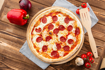 Delicious hot homemade Pepperoni pizza on the wooden table. Pepperoni Pizza - Fresh homemade pizza with pepperoni, cheese and tomato sauce on rustic black stone background wirh copy space.  