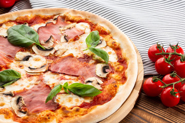 Italian Delicious Fresh Hot Mix Baked Pizza with Melting Cheese, sliced mushrooms , ham, tomato sauce and cheddar serving on textured rustic background. top view.