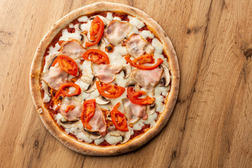 Italian Delicious Fresh Hot Mix Baked Pizza with Melting Cheese, sliced mushrooms , ham, tomato sauce and cheddar serving on textured rustic background. top view.