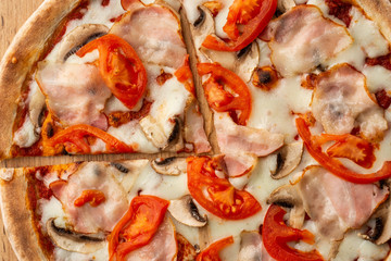 Italian Delicious Fresh Hot Mix Baked Pizza with Melting Cheese, sliced mushrooms , ham, tomato sauce and cheddar serving on textured rustic background. top view.