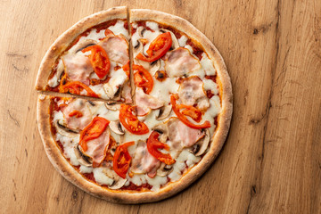 Italian Delicious Fresh Hot Mix Baked Pizza with Melting Cheese, sliced mushrooms , ham, tomato sauce and cheddar serving on textured rustic background. top view.