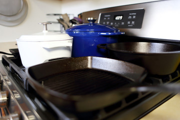 Collection of cast iron cookware on the stove top in a home kitchen.