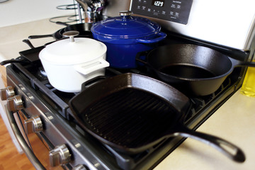 Collection of cast iron cookware on the stove top in a home kitchen.
