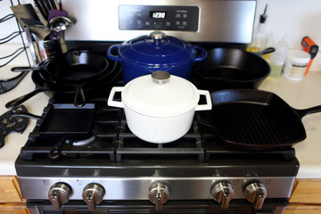 Collection of cast iron cookware on the stove top in a home kitchen.