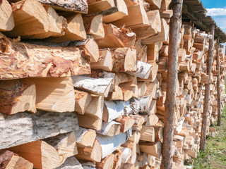 Firewood stacked in a woodpile under a canopy in the open air