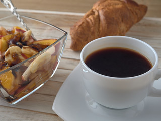 Breakfast.Fruit salad.Black coffee and croissant.On a wooden tray