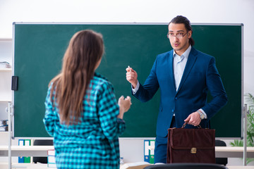 Young handsome teacher and female student in the classroom 