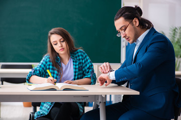 Young handsome teacher and female student in the classroom 