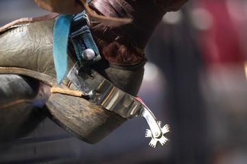 A close up of a cowboy boot and spur on a pipe.