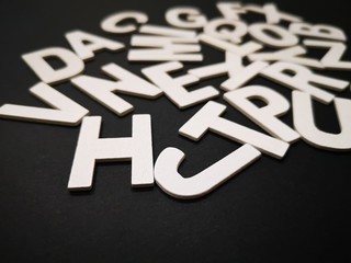 Image of wooden white alphabet letters with black color background.