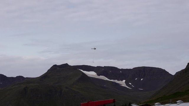 The helicopter transports the building blocks in the mountains.