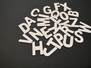 Image of wooden white alphabet letters with black color background.