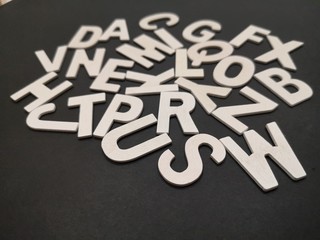 Image of wooden white alphabet letters with black color background.