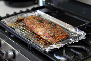 Rack of St. Louis cut style ribs resting in a baking tray on the stove top.