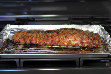 Rack of St. Louis cut style ribs resting in a baking tray on the stove top.