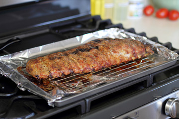 Rack of St. Louis cut style ribs resting in a baking tray on the stove top.