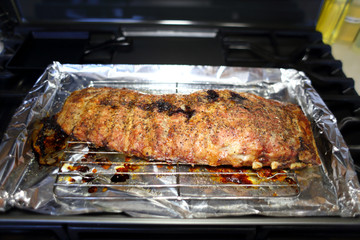 Rack of St. Louis cut style ribs resting in a baking tray on the stove top.