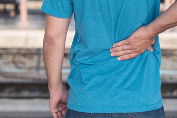man hand holding back pain or herniated spinal disc spot