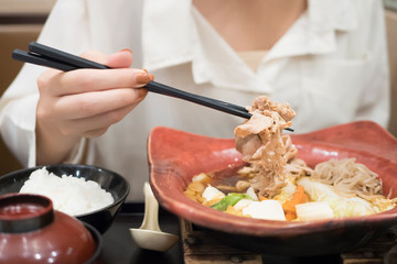 happy smiling woman eating shabu or sukiyaki, Asian Japanese hot pot food concept