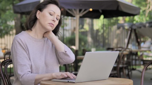 Old Woman with Neck Pain Using Laptop Outdoor
