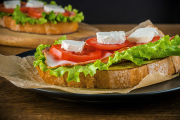 Delicious sandwiches on wooden table with dark background.