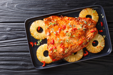 Thai cuisine of salmon fillet baked with pineapples in chili sweet sauce close-up on a plate....