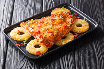 Traditional salmon recipe with pineapples and herbs baked in chili sweet sauce close-up on a plate. horizontal