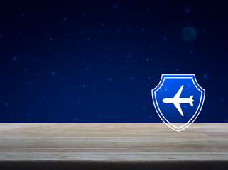 Airplane with shield flat icon on wooden table over fantasy night sky and moon, Business travel insurance and safety concept