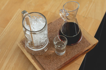 Black coffee cup with ice on wood table in coffee shop. 
