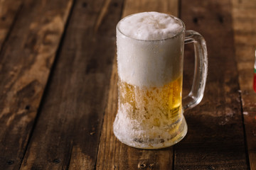 Chilled beer in mug with ice cold drops over a wood surface