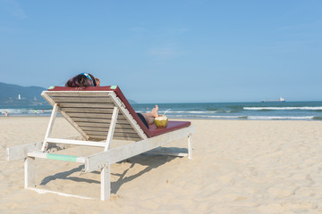 Rear view of woman lying on sandy summer beach chair 