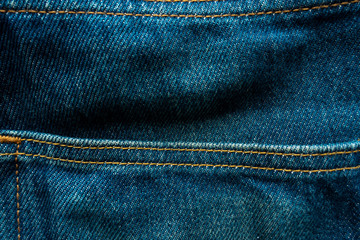 Raw denim jeans faded with yellow stitch for background.