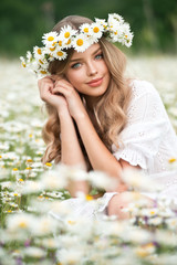 Beautiful young girl with curly hair in chamomile field.  Beautiful girl with chamomile wreath on...