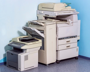 Old broken office equipment stands on the floor in the corner.